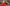 boy in a bright red coat eating a marshmallow on a stick which he has just toasted on the campfire as his mum affectionately holds his arm on a Devon holiday park