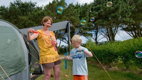 Boy and mum blowing bubbles at Woolacombe beach camping holiday